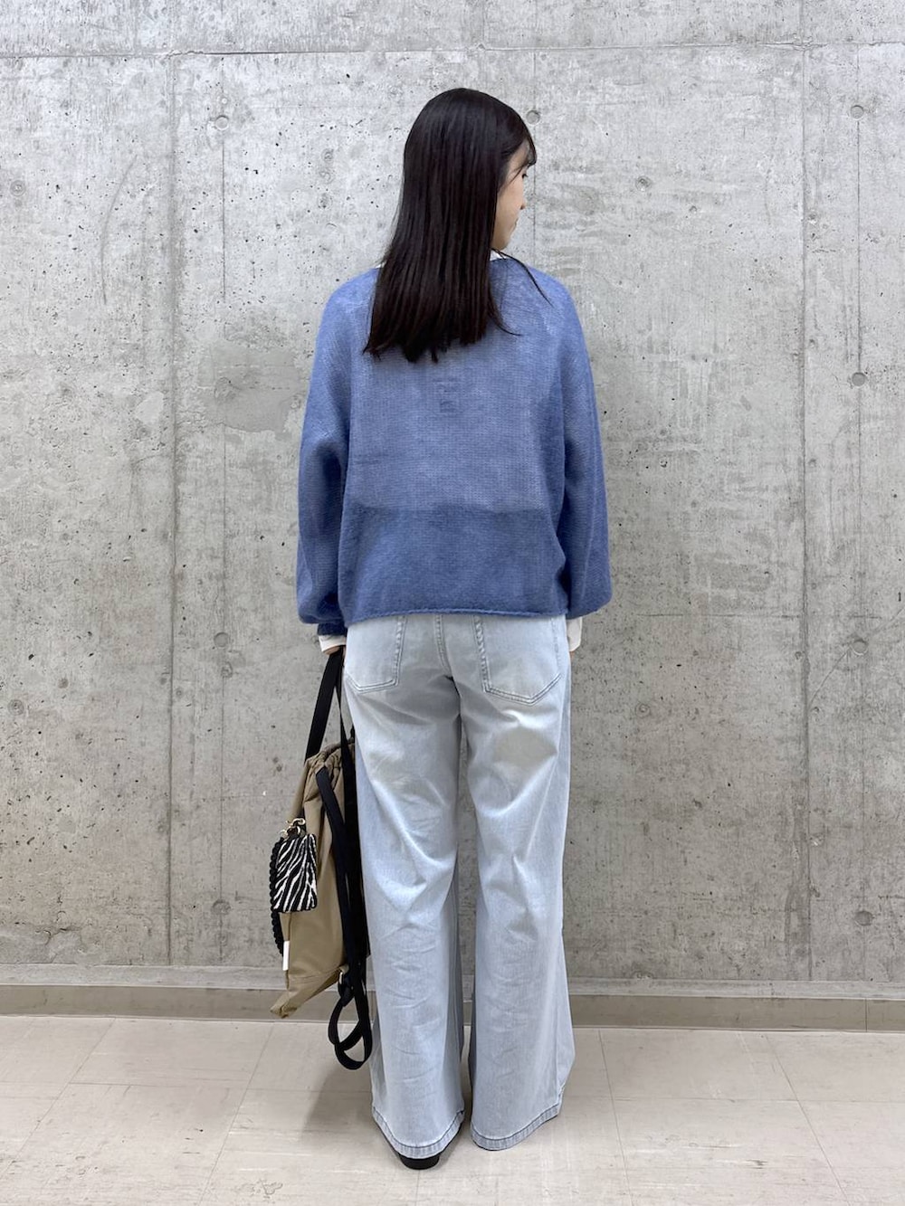 ブルー系のデニムパンツ、ブルー系のニット/セーター、ホワイト系のTシャツ/カットソーを着用したレディースの冬コーディネートの3枚目の写真