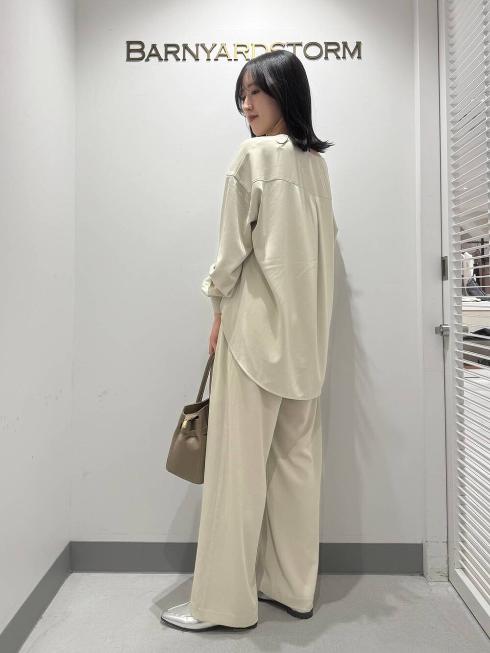 シルバー系のローファー、ベージュ系のショルダーバッグ、ホワイト系のシャツ/ブラウスを着用したレディースの冬コーディネートの3枚目の写真