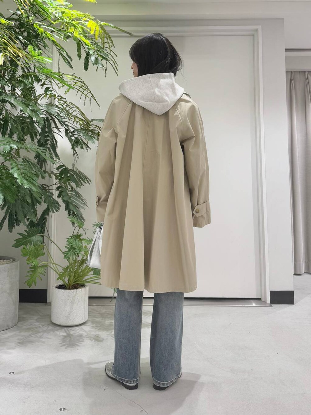 シルバー系のハンドバッグ、シルバー系のローファー、ブルー系のデニムパンツを着用したレディースの冬コーディネートの4枚目の写真