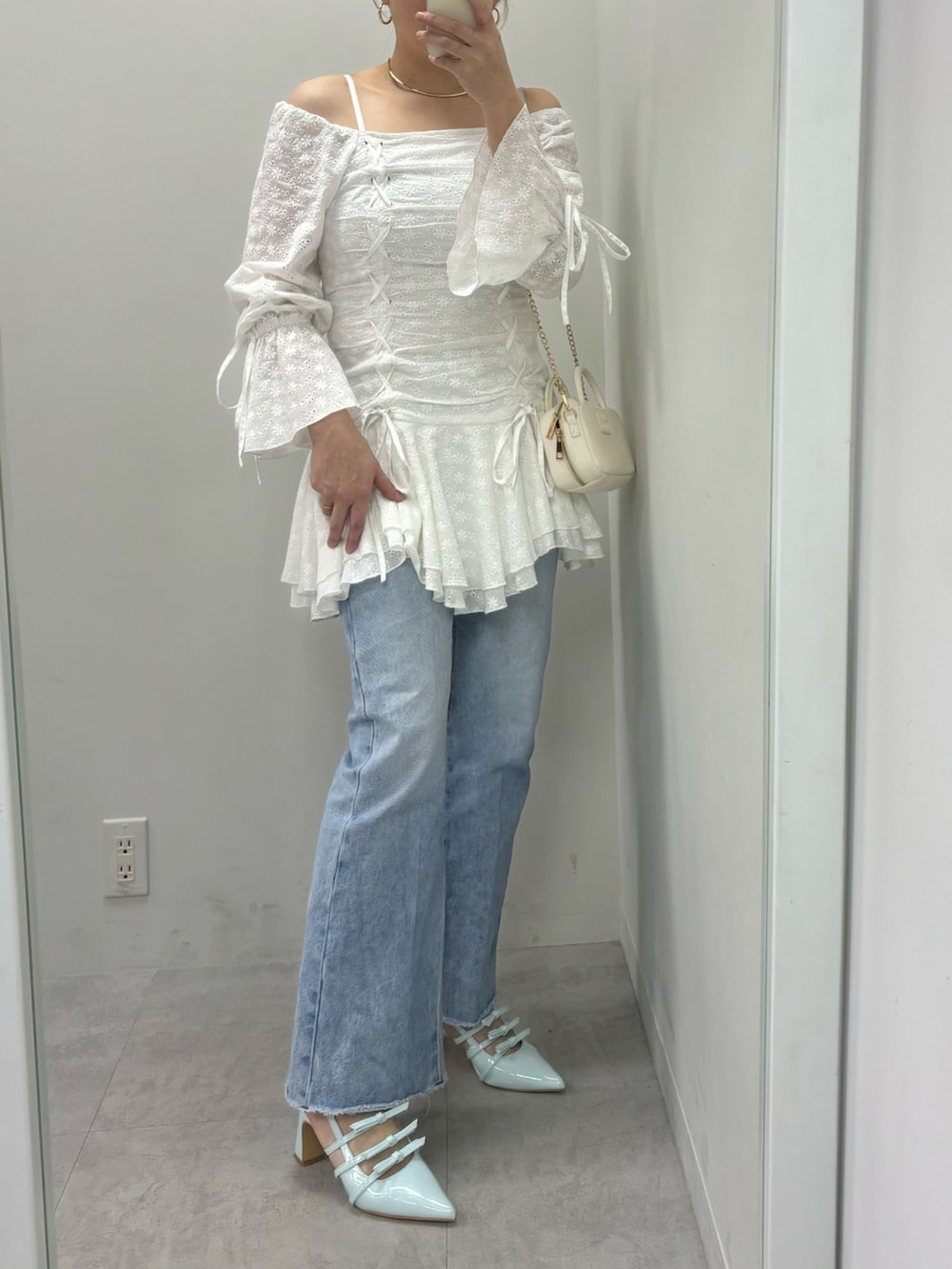 ブルー系のデニムパンツ、ホワイト系のボストンバッグ、ホワイト系のワンピースを着用したレディースの冬コーディネートの2枚目の写真