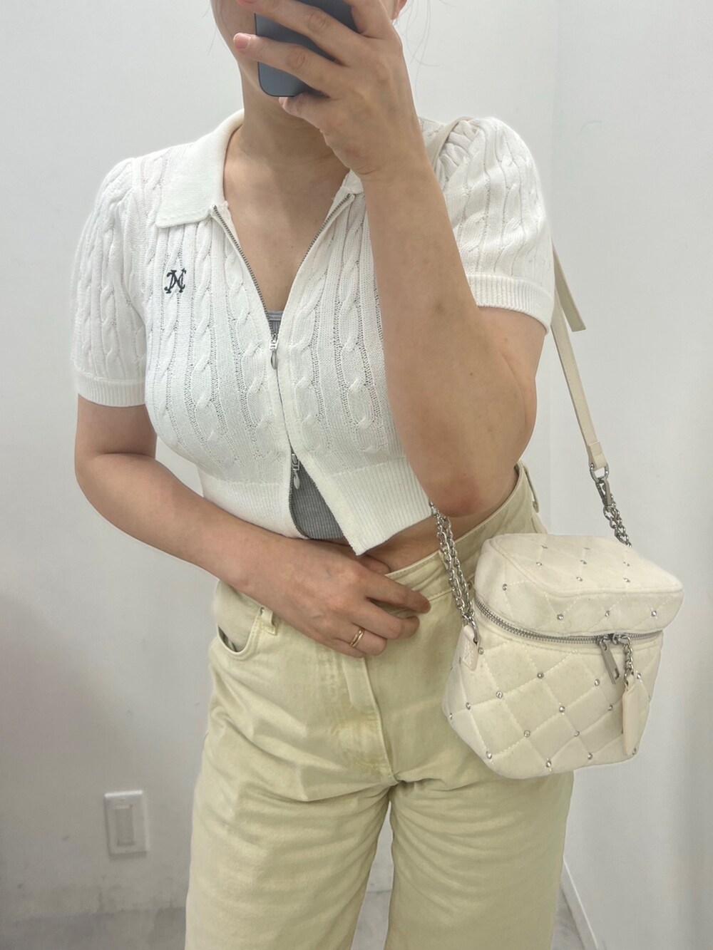 ホワイト系のニット/セーター、ブラック系のショルダーバッグを着用したレディースの夏コーディネートの2枚目の写真