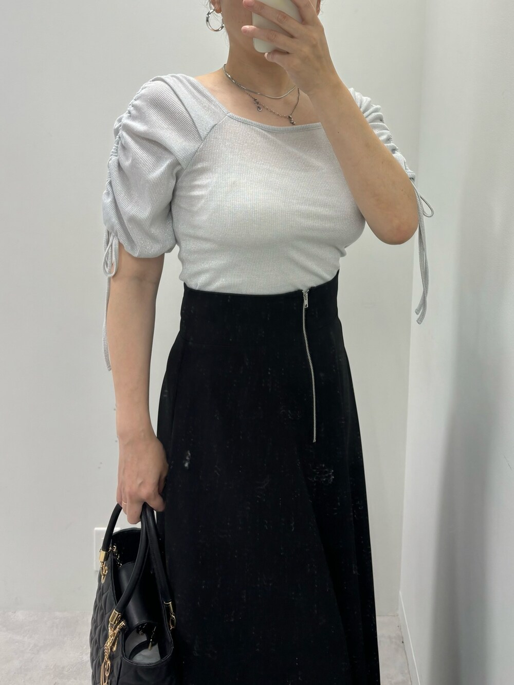 ブラック系のスカート、シルバー系のサンダル、ブラック系のトートバッグを着用したレディースの夏コーディネートの2枚目の写真