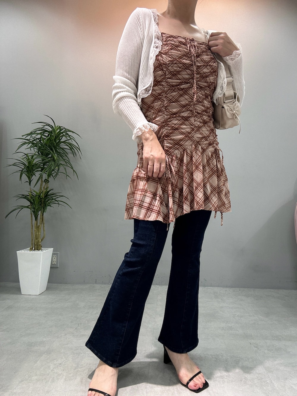 ベージュ系のチュニック、ブルー系のデニムパンツ、ホワイト系のカーディガン/ボレロを着用したレディースの夏コーディネートの2枚目の写真