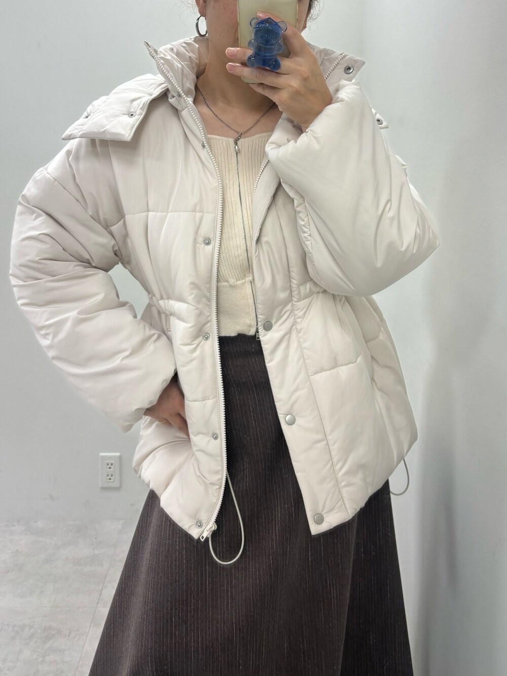 ブラウン系のスカート、ベージュ系のダウンジャケット/コート、ホワイト系のニット/セーターを着用したレディースの冬コーディネートの3枚目の写真