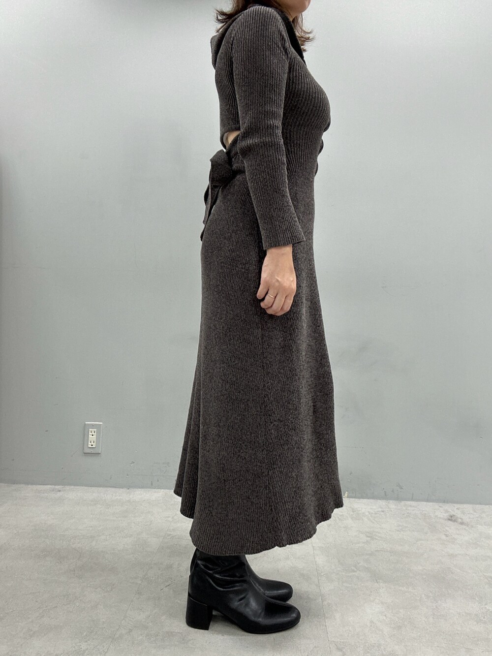 グレー系のワンピース、ブラック系のボストンバッグ、ブラック系のブーツを着用したレディースの秋コーディネートの2枚目の写真