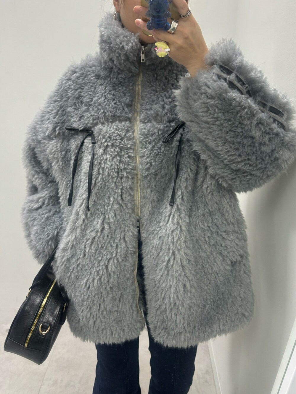 ブルー系のデニムパンツ、ブラック系のショルダーバッグ、グレー系のブルゾンを着用したレディースの秋コーディネートの5枚目の写真