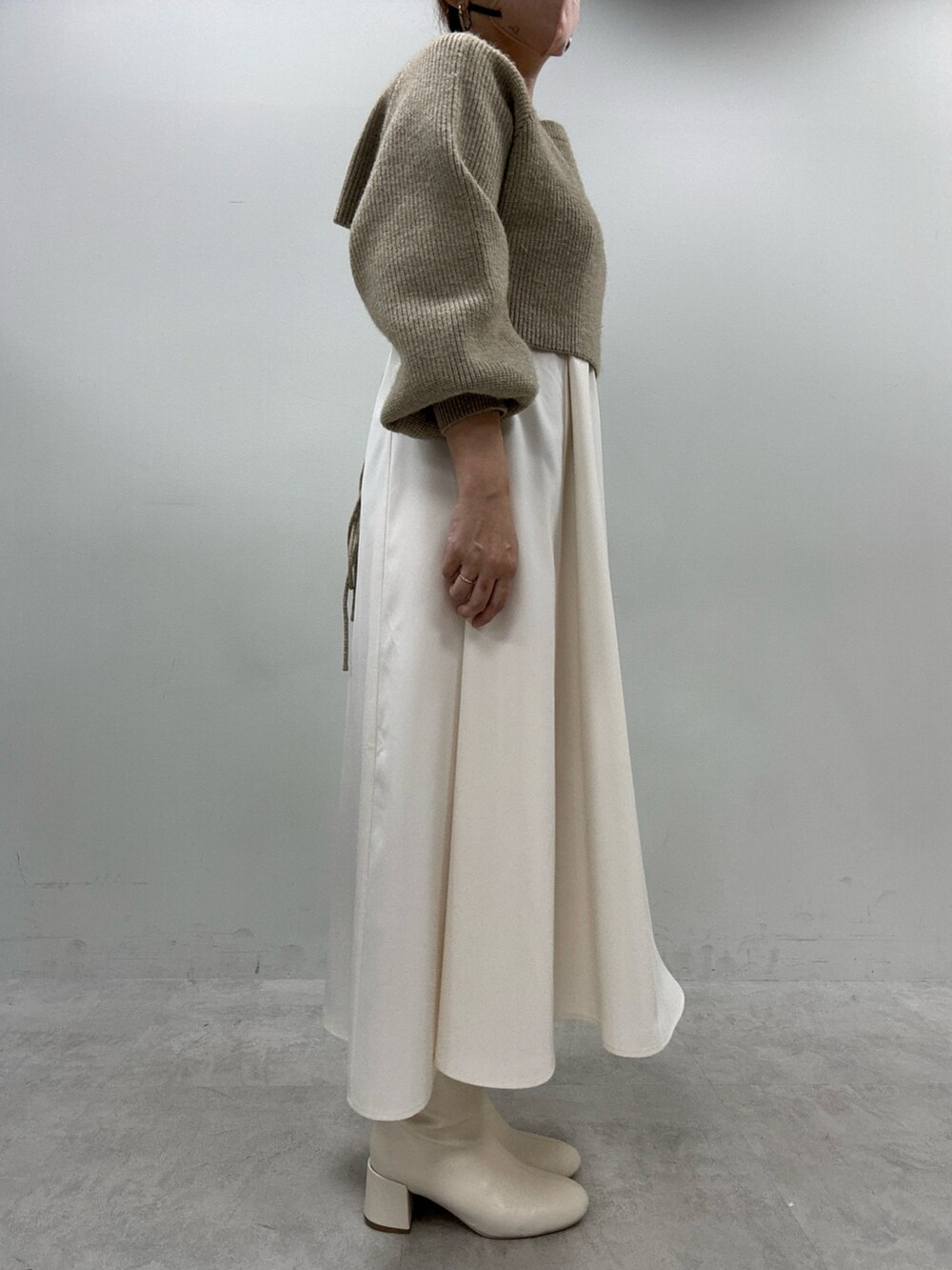 ブラック系のブーツ、ベージュ系のワンピース、イエロー系のボストンバッグを着用したレディースの秋コーディネートの2枚目の写真