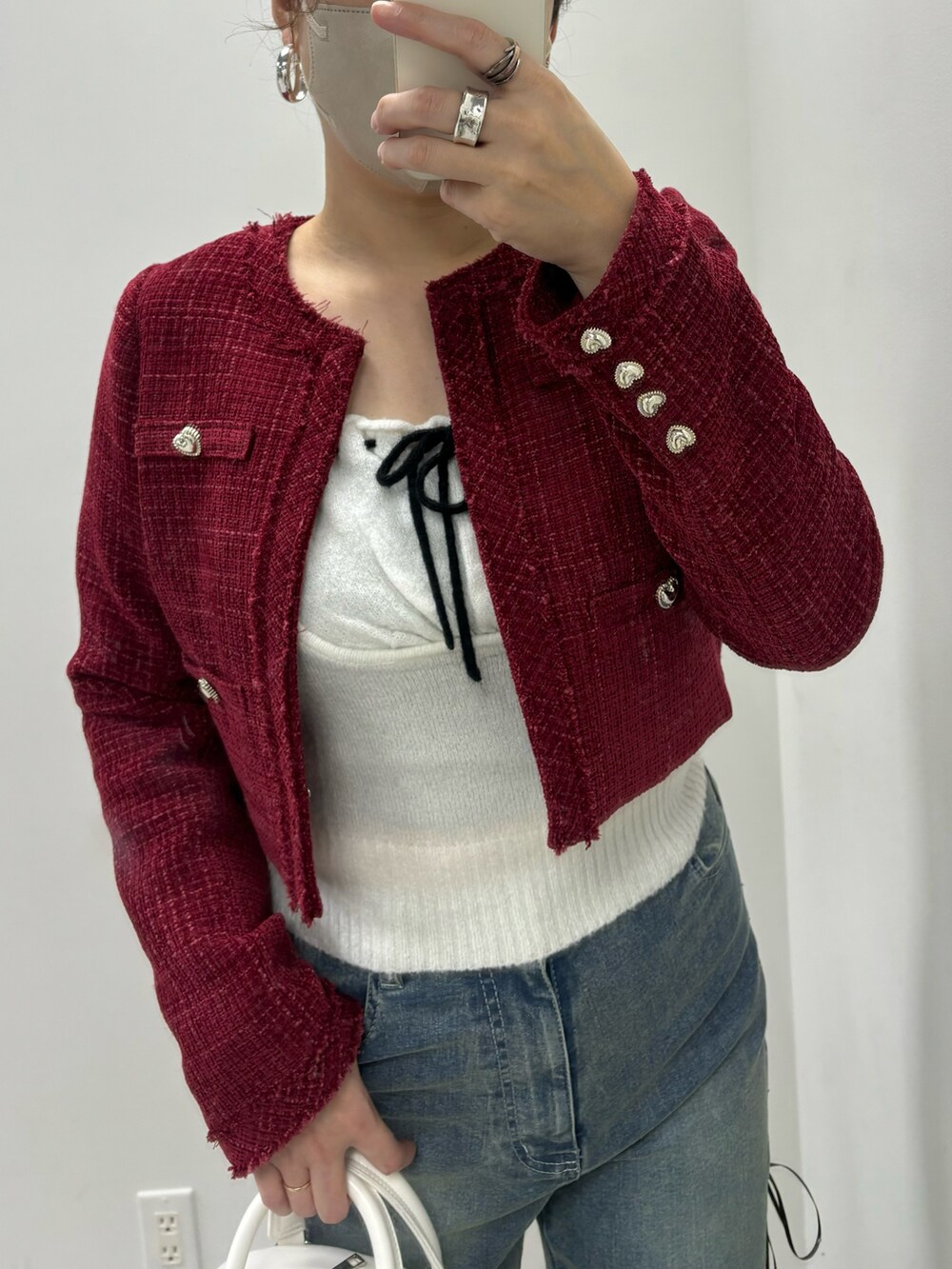 ブルー系のデニムパンツ、ホワイト系のハンドバッグ、レッド系のワンピースを着用したレディースの冬コーディネートの4枚目の写真