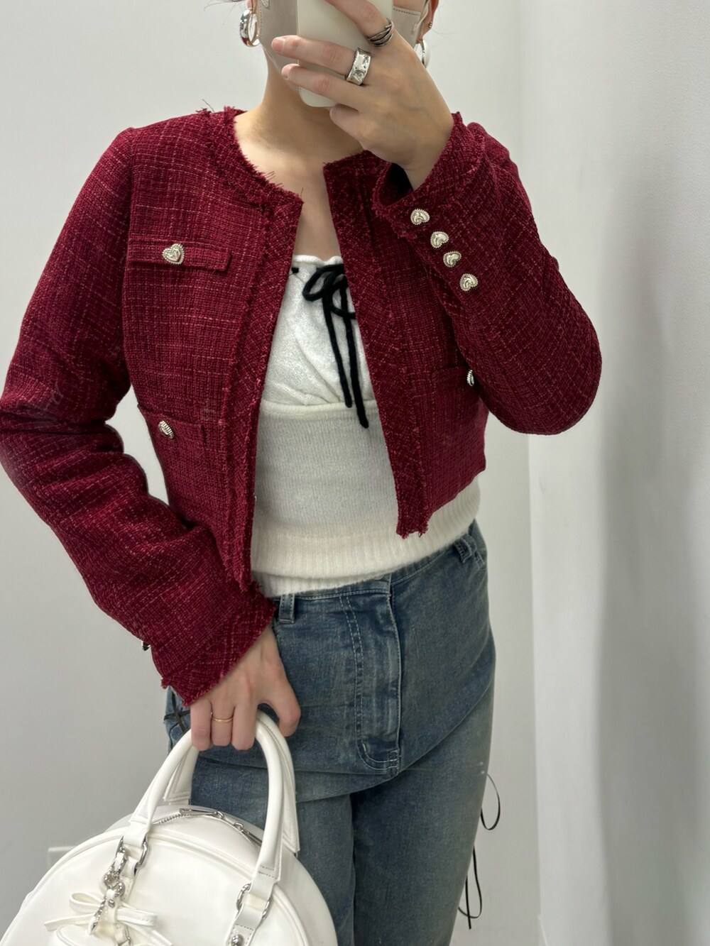 ブルー系のデニムパンツ、ホワイト系のハンドバッグ、レッド系のワンピースを着用したレディースの冬コーディネートの3枚目の写真