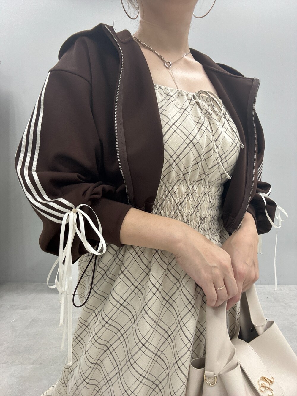 ブラウン系のパーカー、ブラック系のブーツ、ベージュ系のワンピースを着用したレディースの秋コーディネートの4枚目の写真