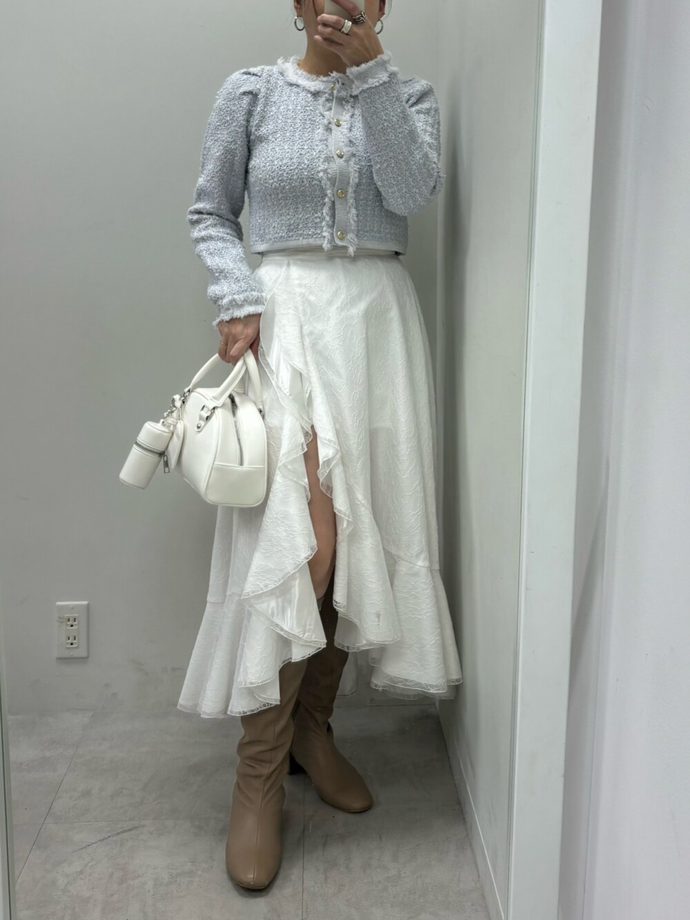 ホワイト系のスカート、ホワイト系のハンドバッグ、ブルー系のカーディガン/ボレロを着用したレディースの冬コーディネートの2枚目の写真