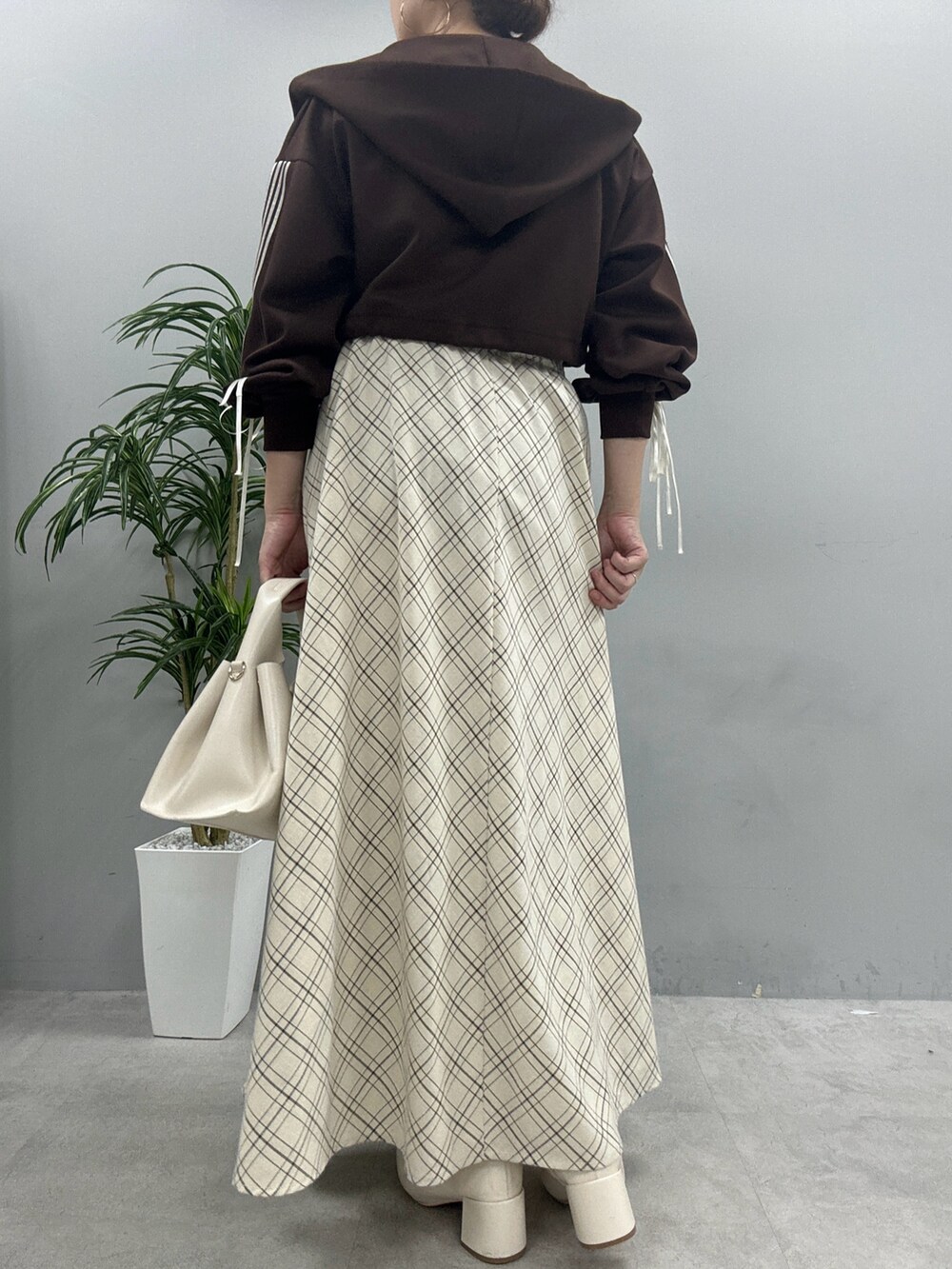 ブラウン系のパーカー、ブラック系のブーツ、ベージュ系のワンピースを着用したレディースの秋コーディネートの3枚目の写真