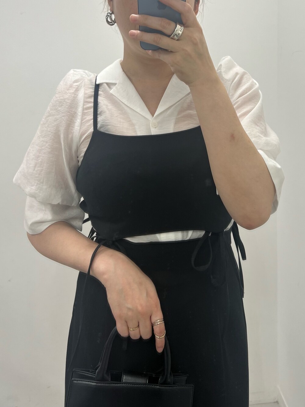 ブラック系のワンピース、ホワイト系のショルダーバッグ、ホワイト系のシャツ/ブラウスを着用したレディースの春コーディネートの2枚目の写真