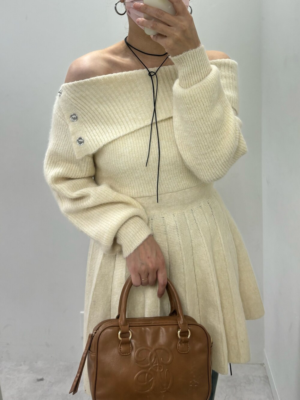 ホワイト系のワンピース、ブルー系のデニムパンツ、ブラック系のブーツを着用したレディースの秋コーディネートの3枚目の写真