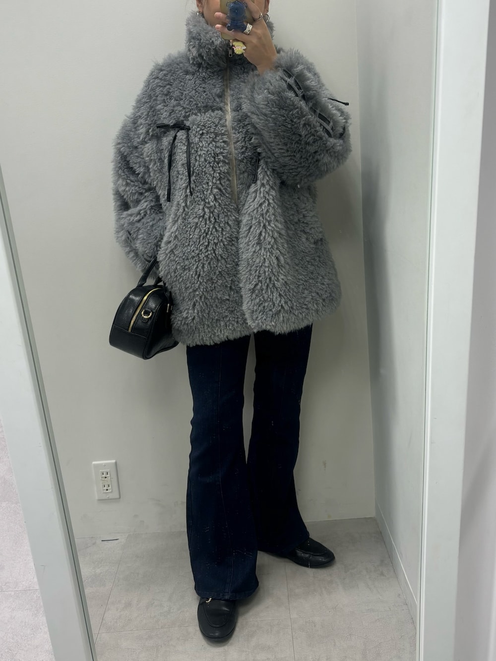 ブルー系のデニムパンツ、ブラック系のショルダーバッグ、グレー系のブルゾンを着用したレディースの秋コーディネートの2枚目の写真