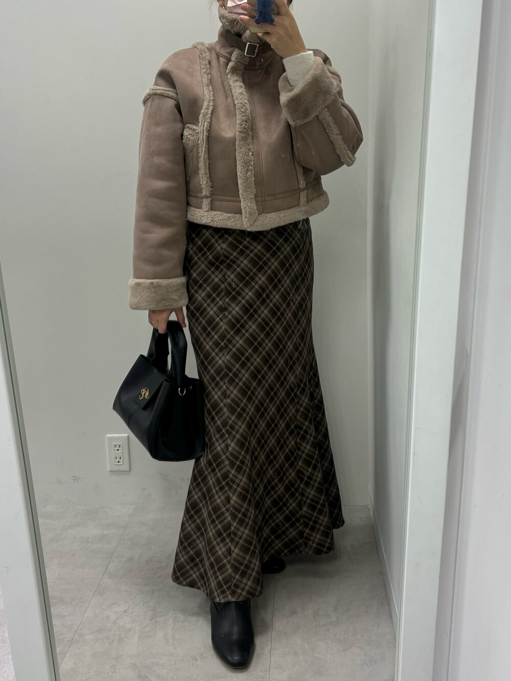 ブラウン系のスカート、ホワイト系のハンドバッグ、ブラウン系のムートンコートを着用したレディースの秋コーディネートの5枚目の写真