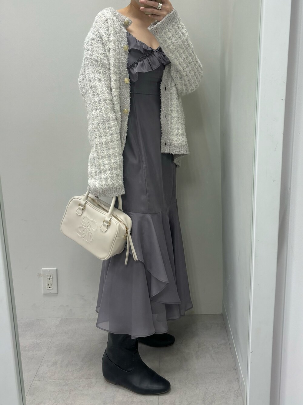 グレー系のワンピース、ブルー系のカーディガン/ボレロ、イエロー系のボストンバッグを着用したレディースの冬コーディネートの2枚目の写真