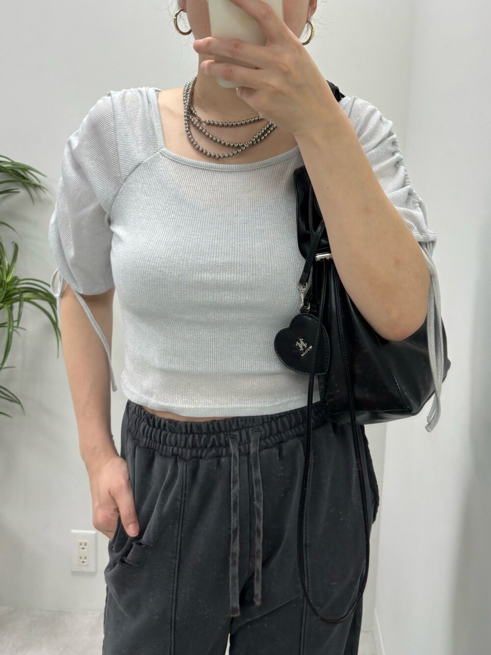 グレー系のパンツ、ブラック系のハンドバッグ、シルバー系のTシャツ/カットソーを着用したレディースの春コーディネートの2枚目の写真