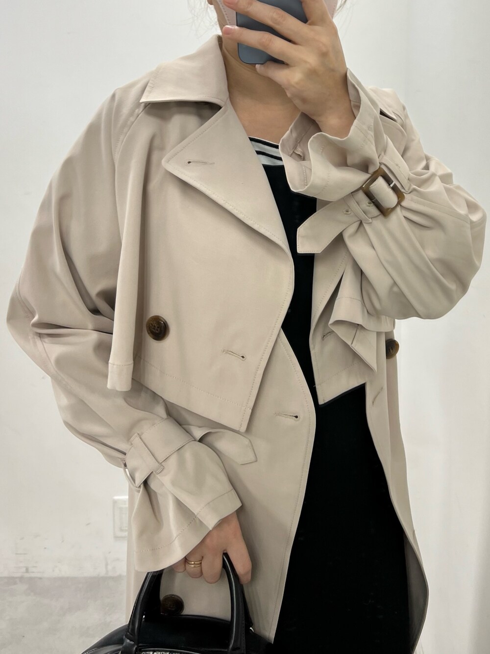 ホワイト系のワンピース、ブラック系のワンピース、ベージュ系のトレンチコートを着用したレディースの冬コーディネートの2枚目の写真