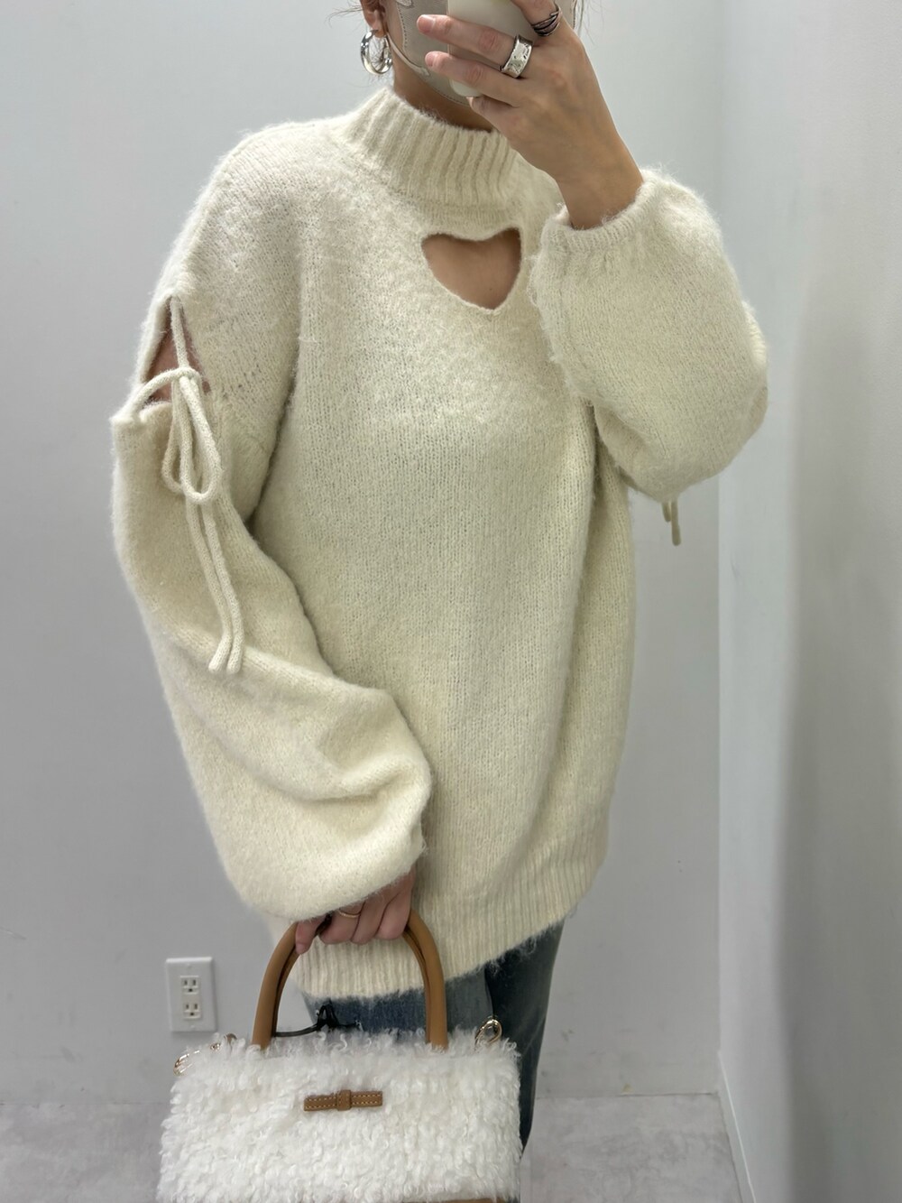 ブルー系のデニムパンツ、ブラウン系のブーツ、ホワイト系のニット/セーターを着用したレディースの冬コーディネートの2枚目の写真