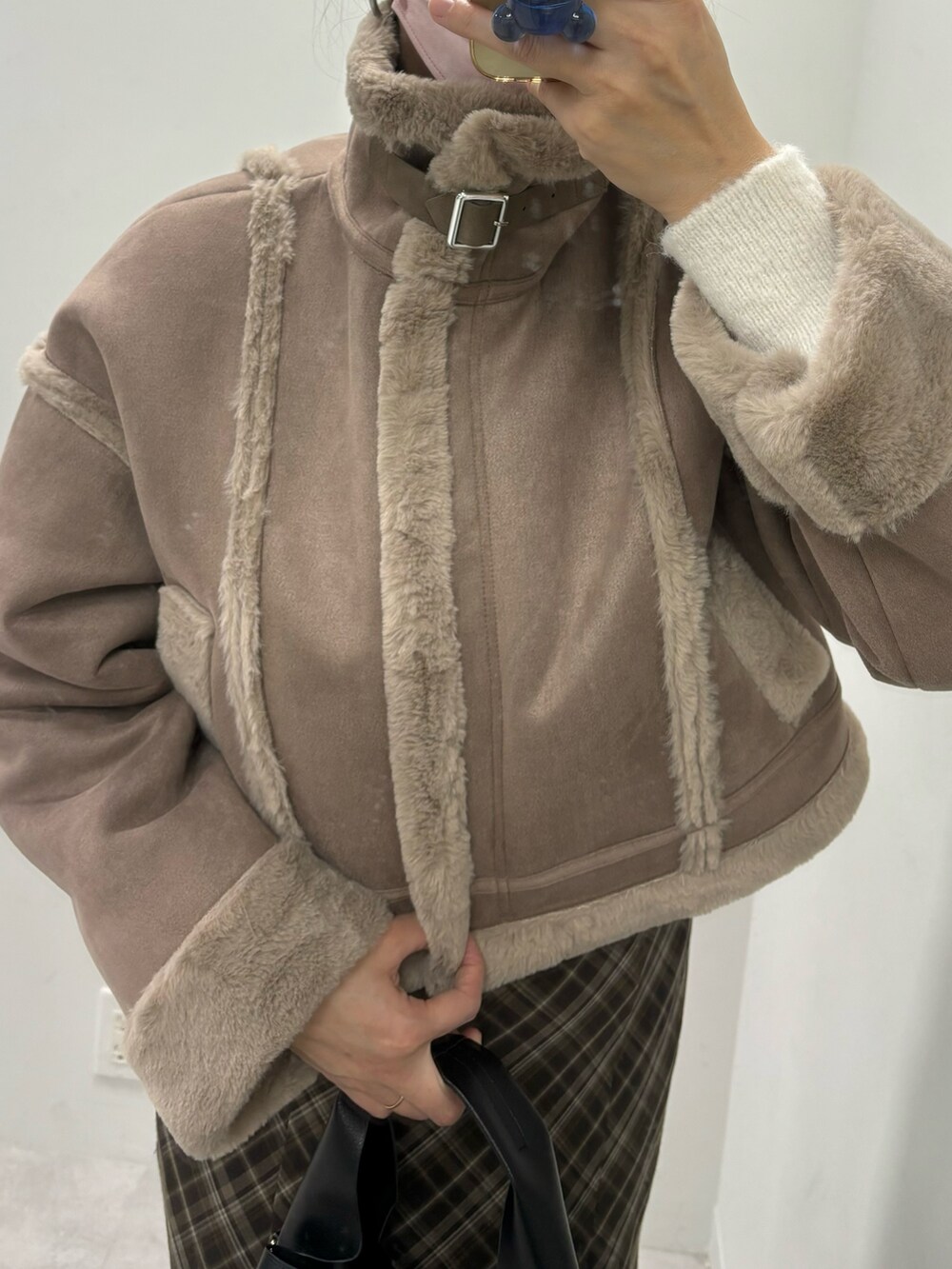 ブラウン系のスカート、ホワイト系のハンドバッグ、ブラウン系のムートンコートを着用したレディースの秋コーディネートの6枚目の写真