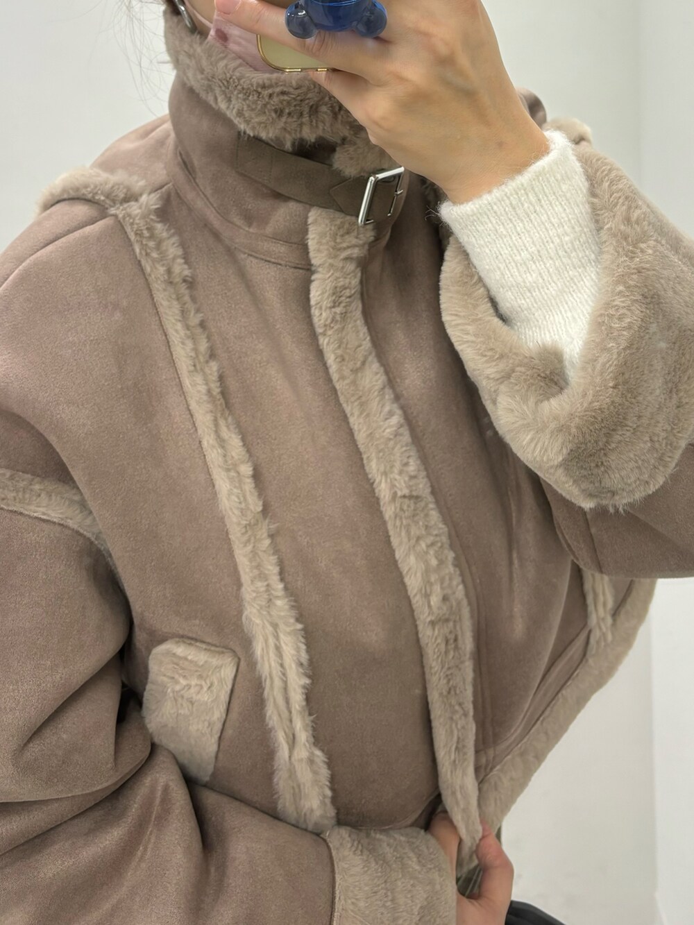 ブラウン系のスカート、ホワイト系のハンドバッグ、ブラウン系のムートンコートを着用したレディースの秋コーディネートの7枚目の写真