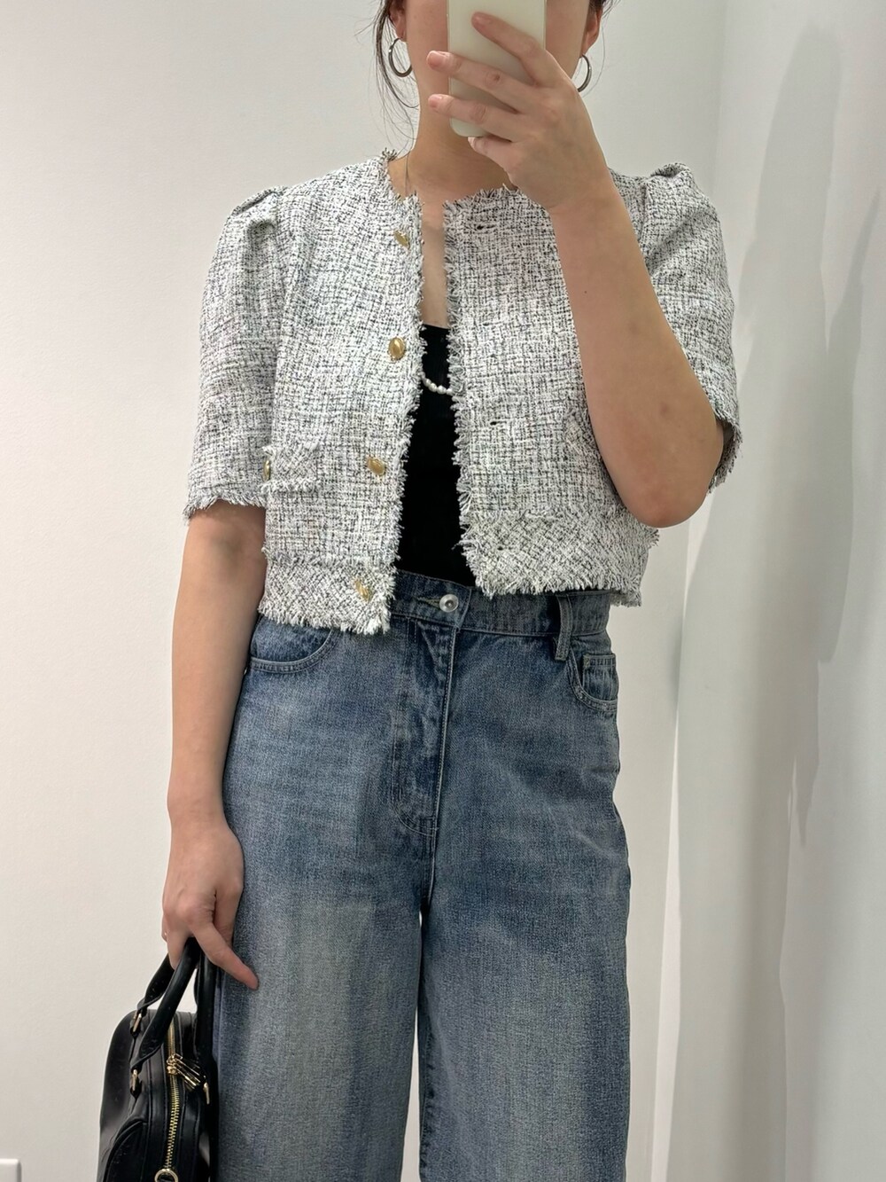 ブルー系のデニムパンツ、ブラック系のノーカラージャケット、ベージュ系のボストンバッグを着用したレディースの春コーディネートの2枚目の写真