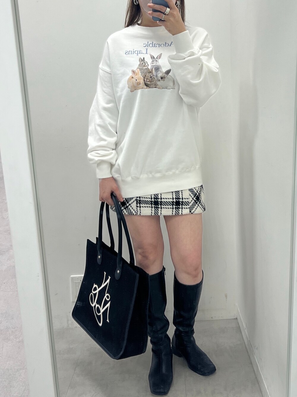 ホワイト系のスウェット、ホワイト系のスカート、ブラック系のブーツを着用したレディースの春コーディネートの2枚目の写真