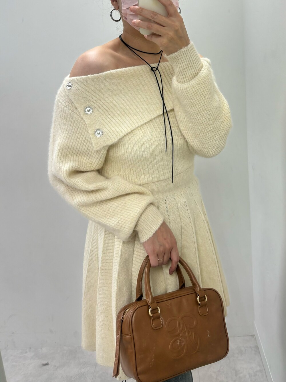 ホワイト系のワンピース、ブルー系のデニムパンツ、ブラック系のブーツを着用したレディースの秋コーディネートの4枚目の写真