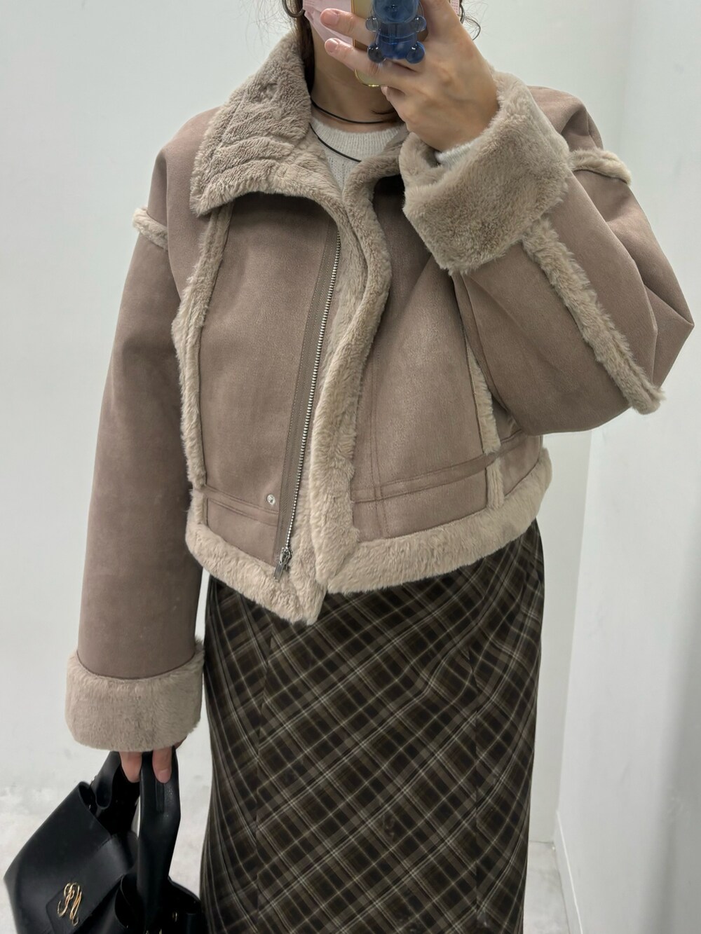 ブラウン系のスカート、ホワイト系のハンドバッグ、ブラウン系のムートンコートを着用したレディースの秋コーディネートの2枚目の写真