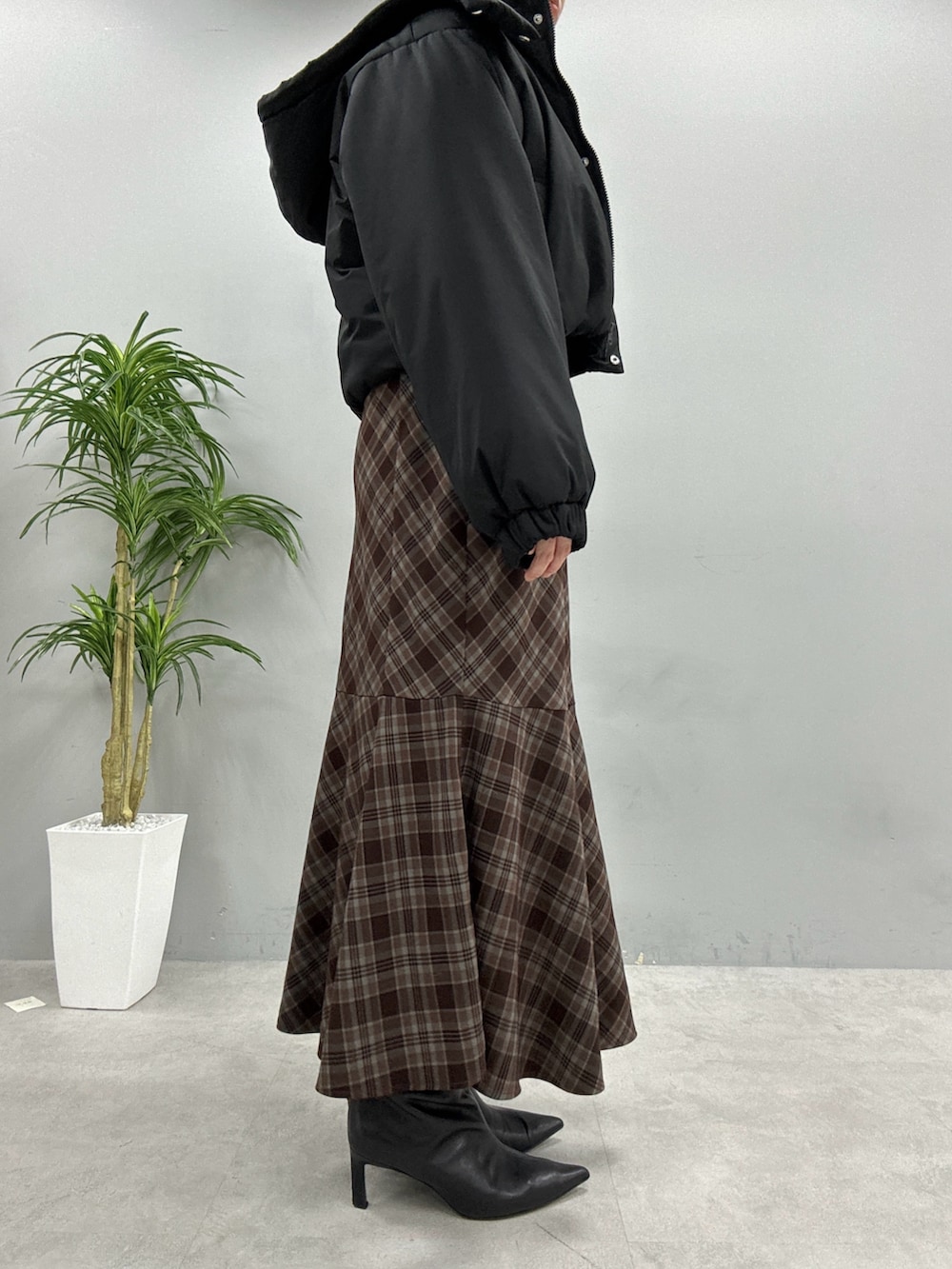 ブラウン系のスカート、ブラック系のショルダーバッグ、ブラック系のダウンジャケット/コートを着用したレディースの秋コーディネートの2枚目の写真