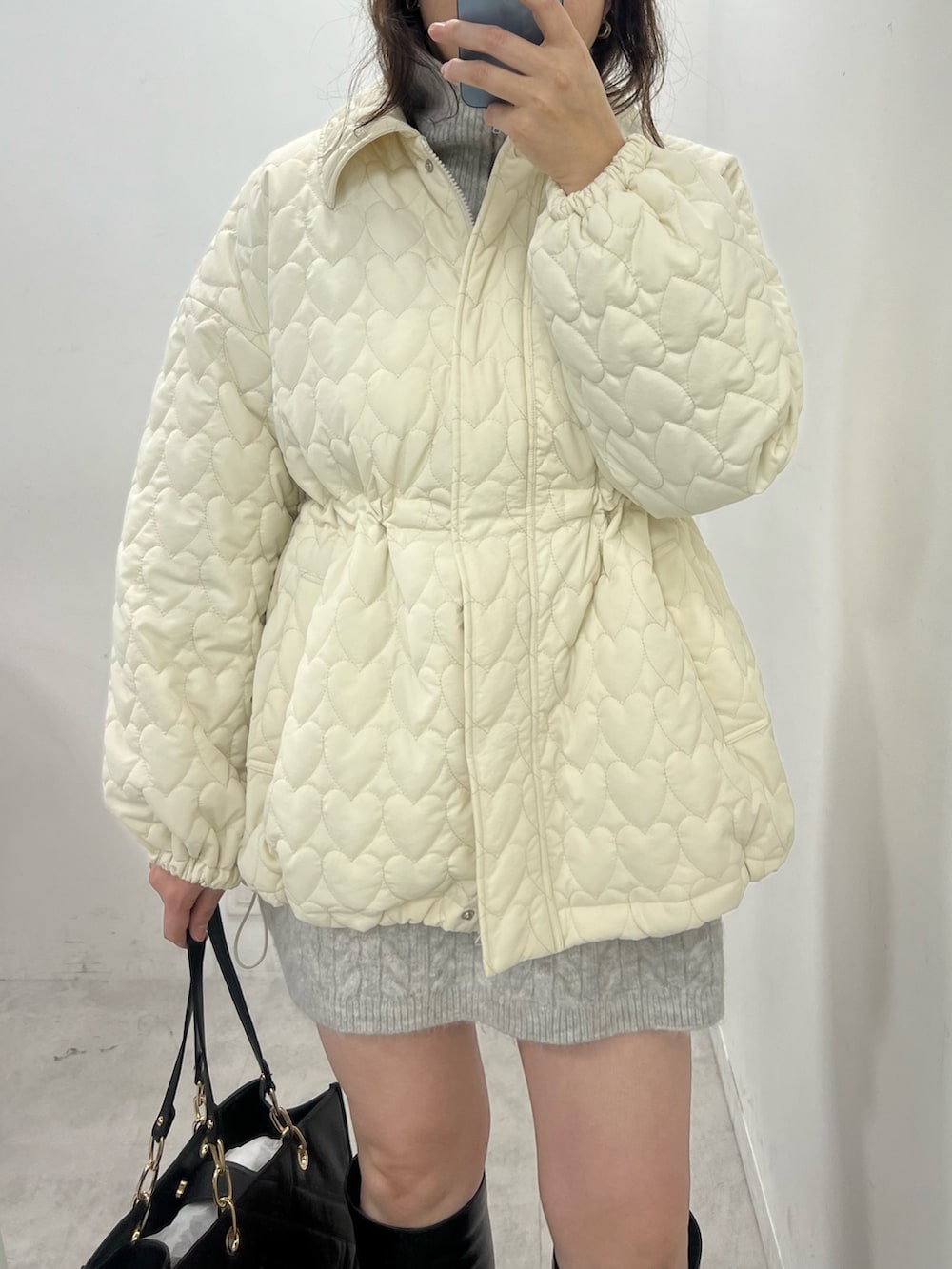 グレー系のワンピース、ホワイト系のその他アウター、ブラック系のトートバッグを着用したレディースの冬コーディネートの2枚目の写真