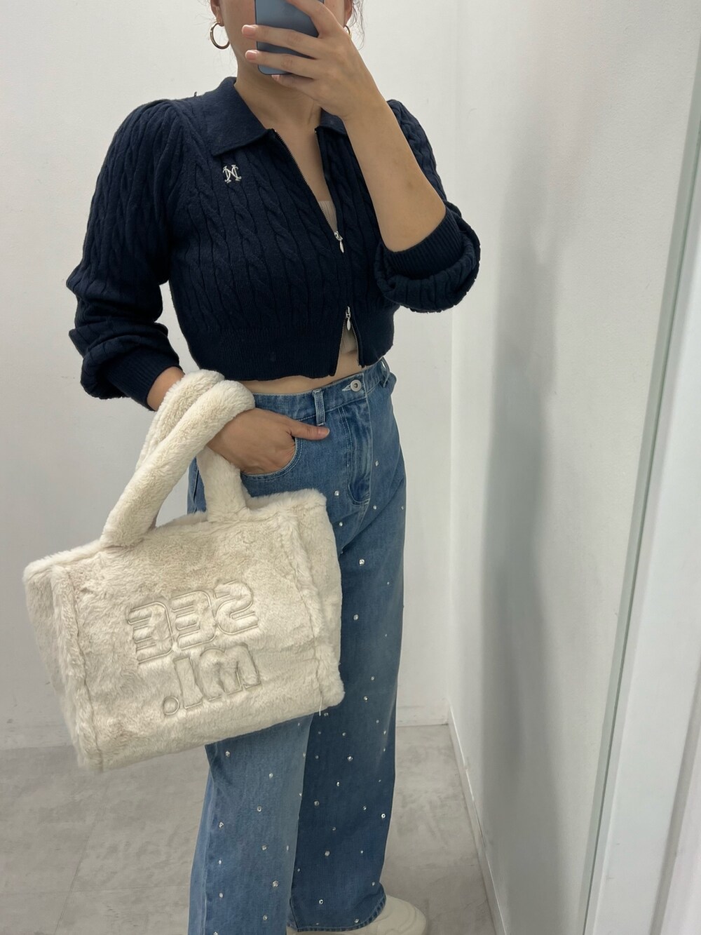 ブルー系のデニムパンツ、ブルー系のニット/セーター、ホワイト系のスニーカーを着用したレディースの秋コーディネートの2枚目の写真