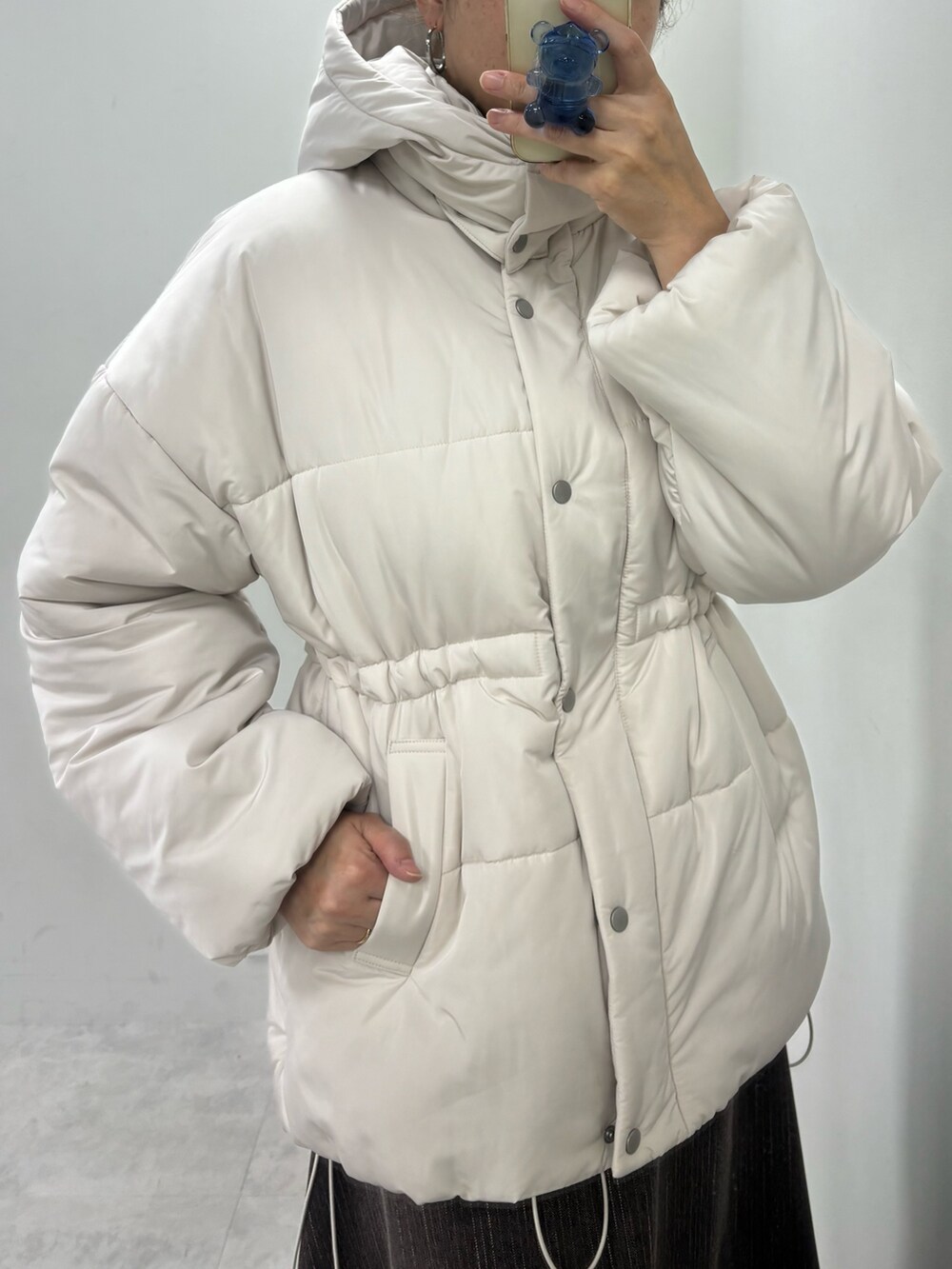 ブラウン系のスカート、ホワイト系のニット/セーター、ベージュ系のダウンジャケット/コートを着用したレディースの秋コーディネートの5枚目の写真