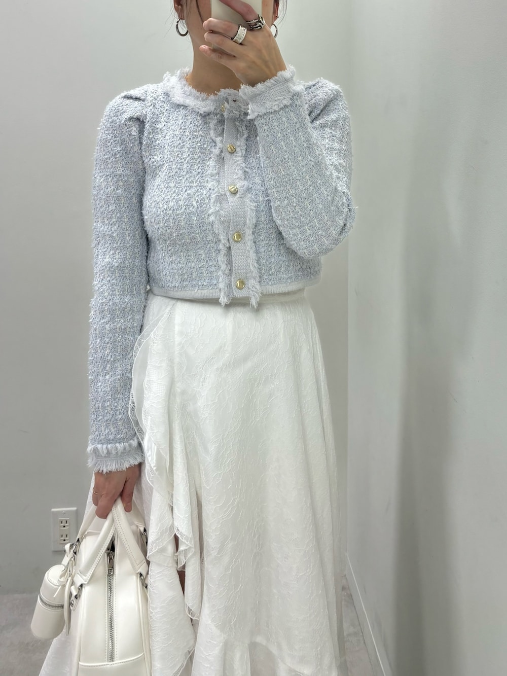 ホワイト系のスカート、ホワイト系のハンドバッグ、ブルー系のカーディガン/ボレロを着用したレディースの冬コーディネートの3枚目の写真