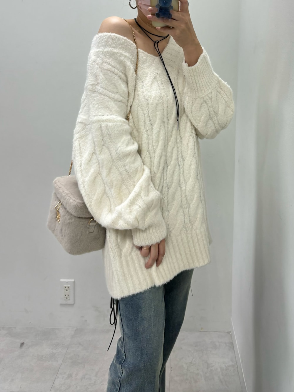 ブルー系のデニムパンツ、ベージュ系のニット/セーター、ブラック系のブーツを着用したレディースの秋コーディネートの3枚目の写真