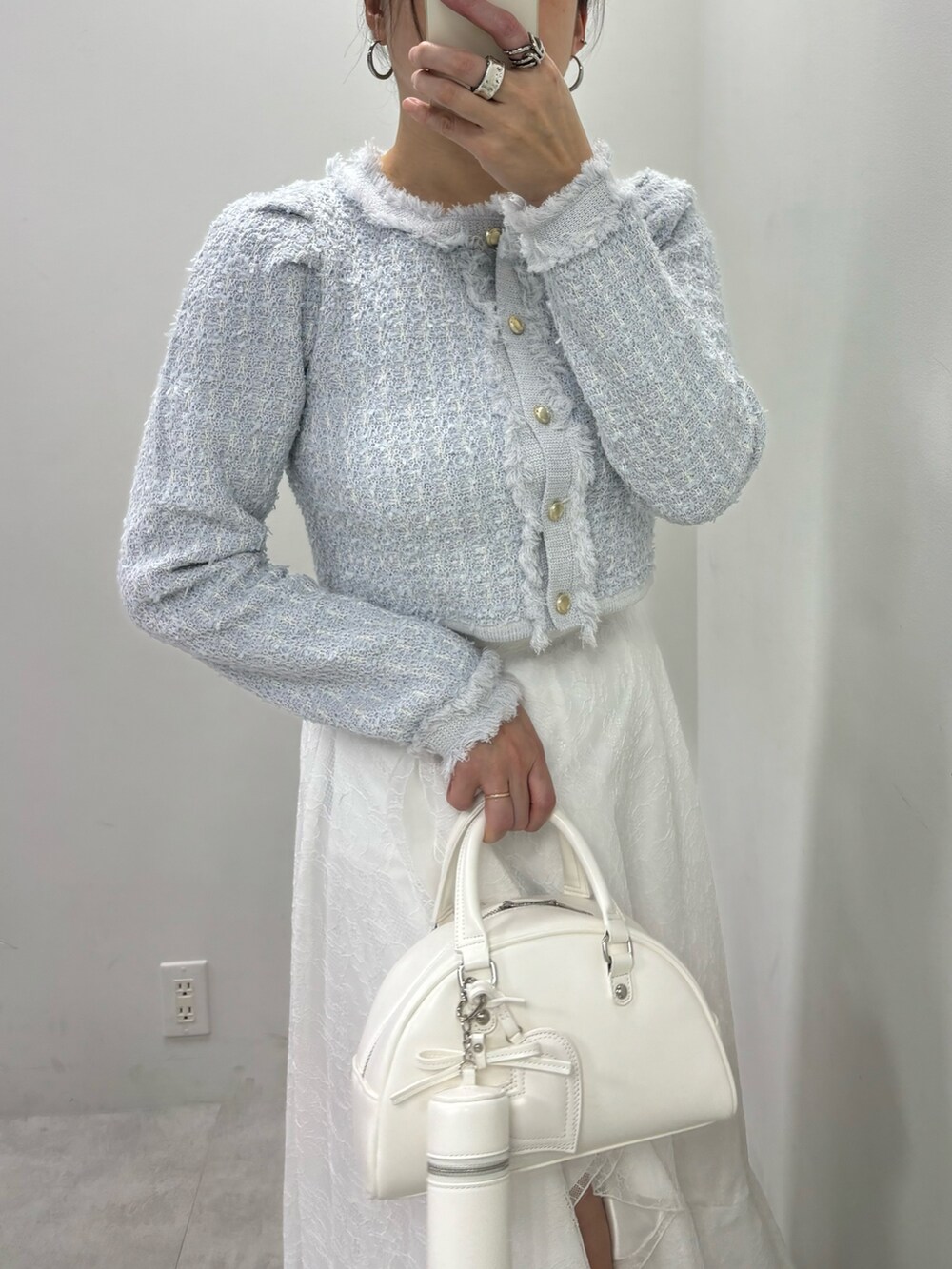 ホワイト系のスカート、ホワイト系のハンドバッグ、ブルー系のカーディガン/ボレロを着用したレディースの冬コーディネートの4枚目の写真