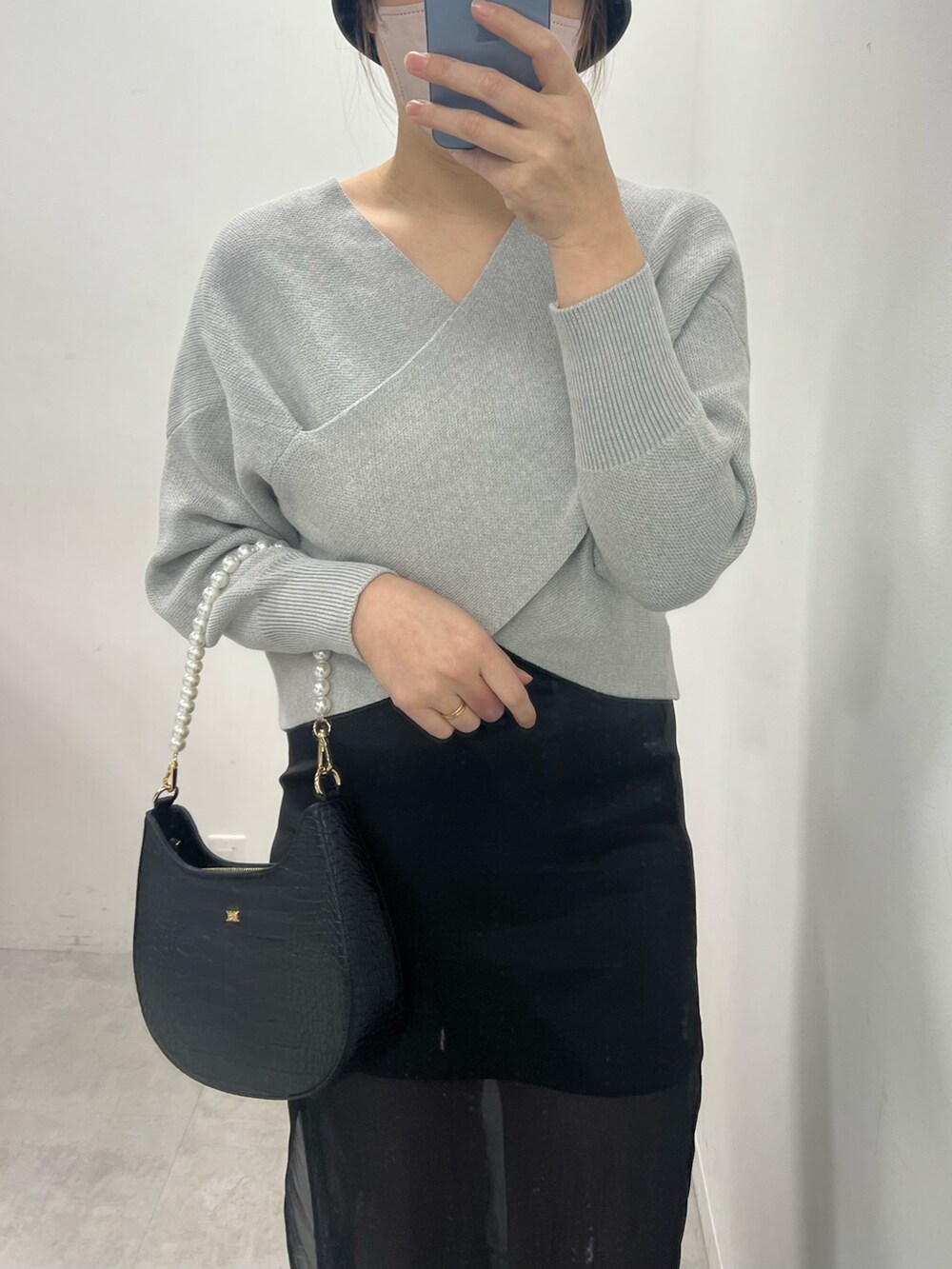 ブラック系のスカート、グレー系のニット/セーター、ブラック系のブーツを着用したレディースの冬コーディネートの2枚目の写真