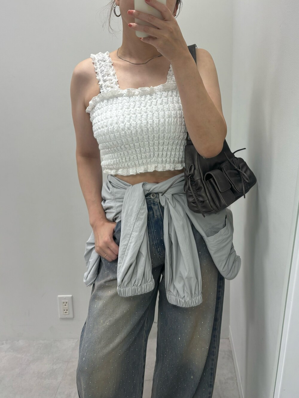 ブラック系のデニムパンツ、ホワイト系のタンクトップ、グレー系のナイロンジャケットを着用したレディースの夏コーディネートの2枚目の写真