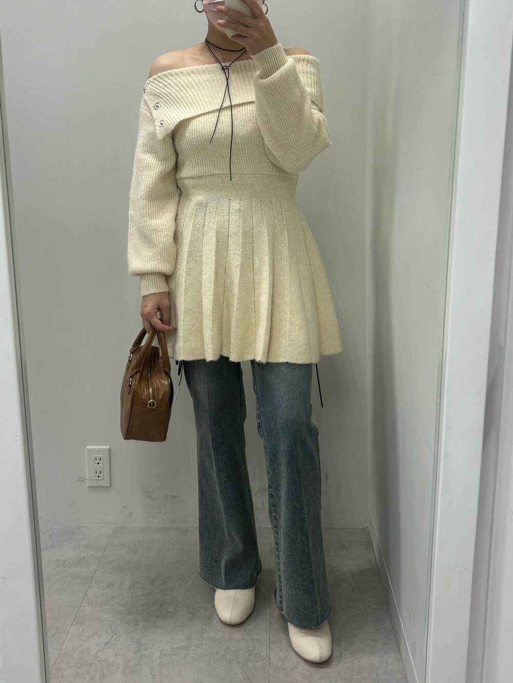 ホワイト系のワンピース、ブルー系のデニムパンツ、ブラック系のブーツを着用したレディースの秋コーディネートの2枚目の写真