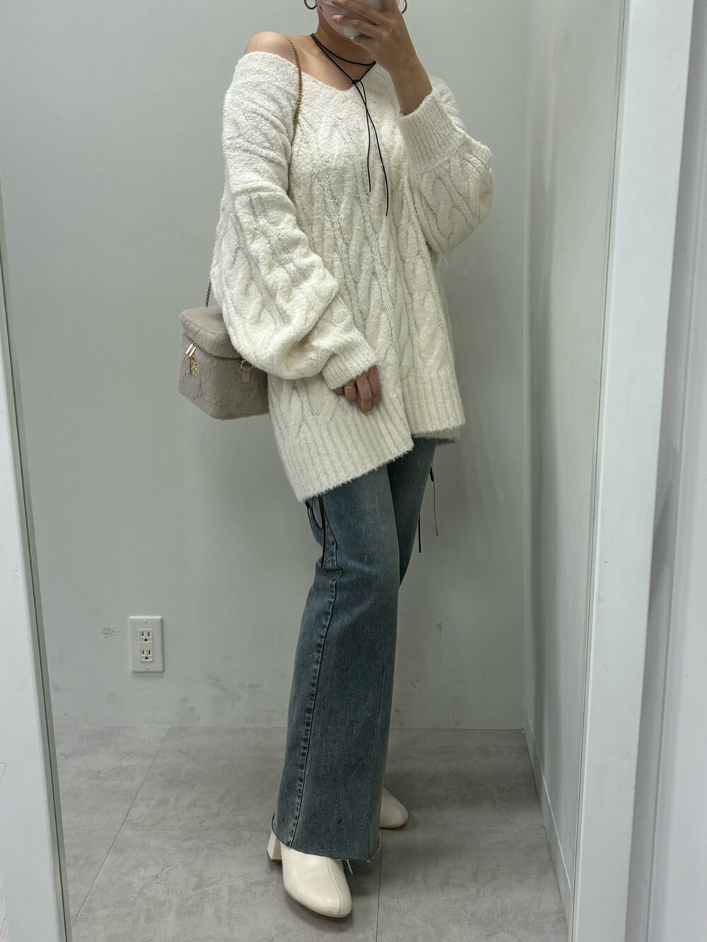 ブルー系のデニムパンツ、ベージュ系のニット/セーター、ブラック系のブーツを着用したレディースの秋コーディネートの2枚目の写真