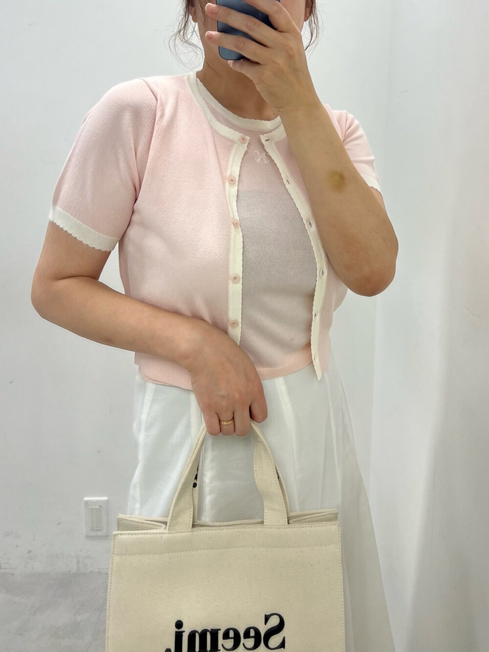 ホワイト系のスカート、ブラック系のサンダル、ピンク系のアンサンブルを着用したレディースの夏コーディネートの2枚目の写真