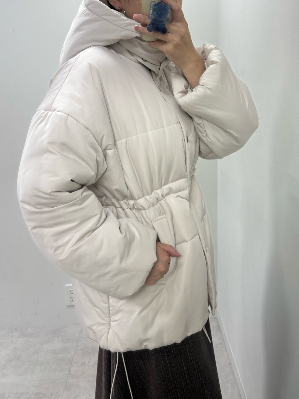 ブラウン系のスカート、ホワイト系のニット/セーター、ベージュ系のダウンジャケット/コートを着用したレディースの秋コーディネートの6枚目の写真