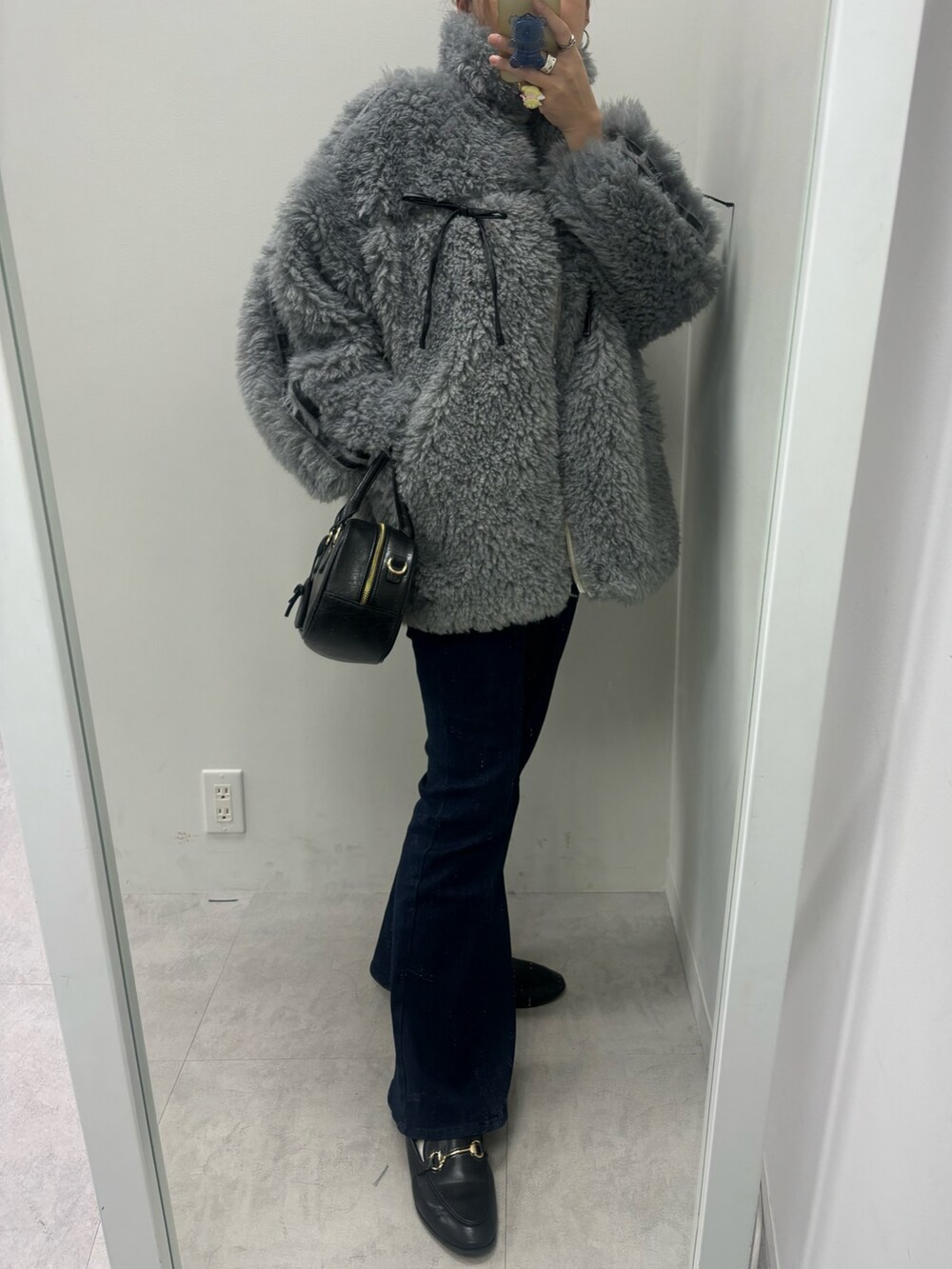 ブルー系のデニムパンツ、ブラック系のショルダーバッグ、グレー系のブルゾンを着用したレディースの秋コーディネートの3枚目の写真