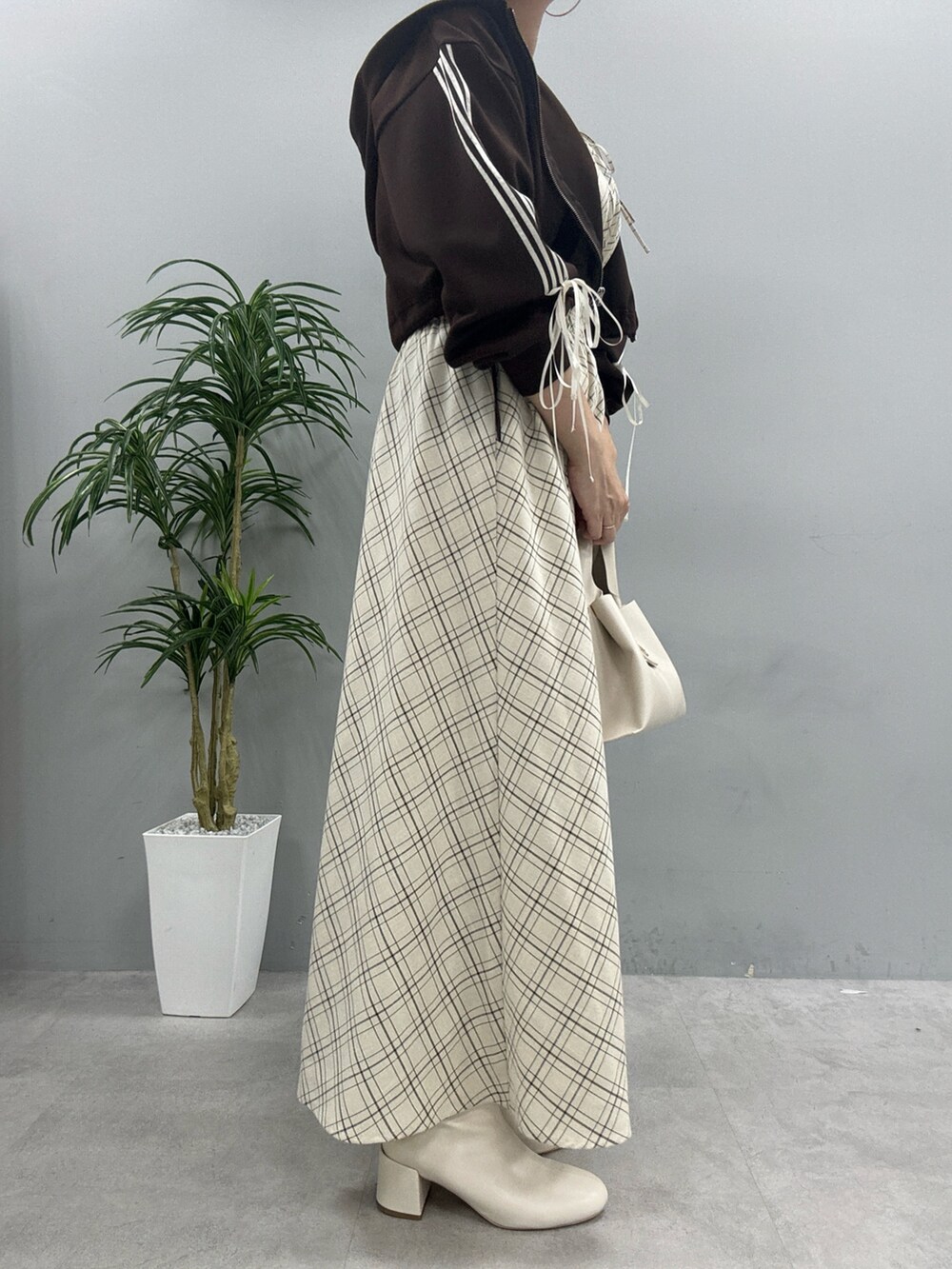 ブラウン系のパーカー、ブラック系のブーツ、ベージュ系のワンピースを着用したレディースの秋コーディネートの2枚目の写真