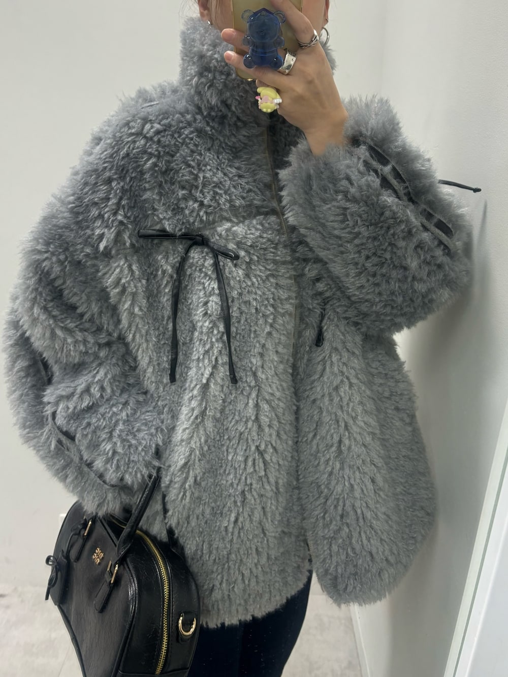 ブルー系のデニムパンツ、ブラック系のショルダーバッグ、グレー系のブルゾンを着用したレディースの秋コーディネートの4枚目の写真