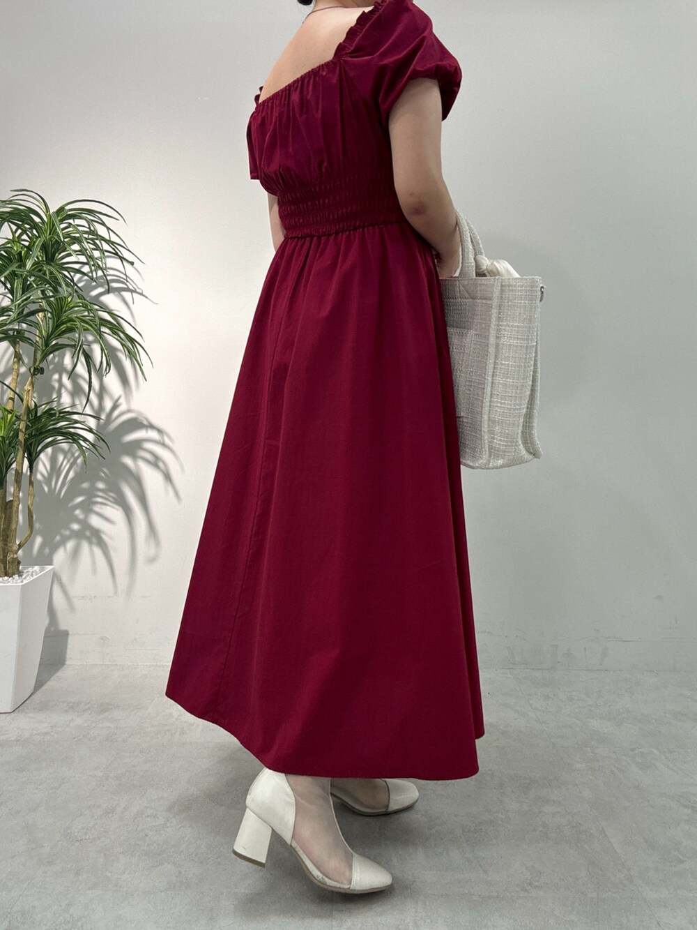 レッド系のワンピース、ホワイト系のトートバッグ、ホワイト系のブーツを着用したレディースの夏コーディネートの2枚目の写真