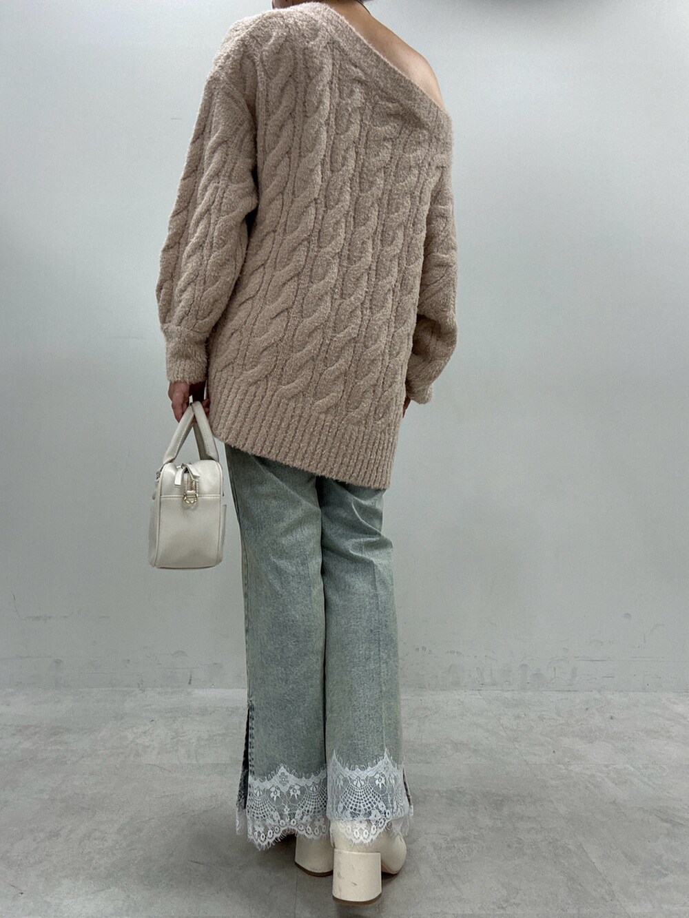 ブルー系のデニムパンツ、ベージュ系のニット/セーター、ブラック系のブーツを着用したレディースの秋コーディネートの3枚目の写真