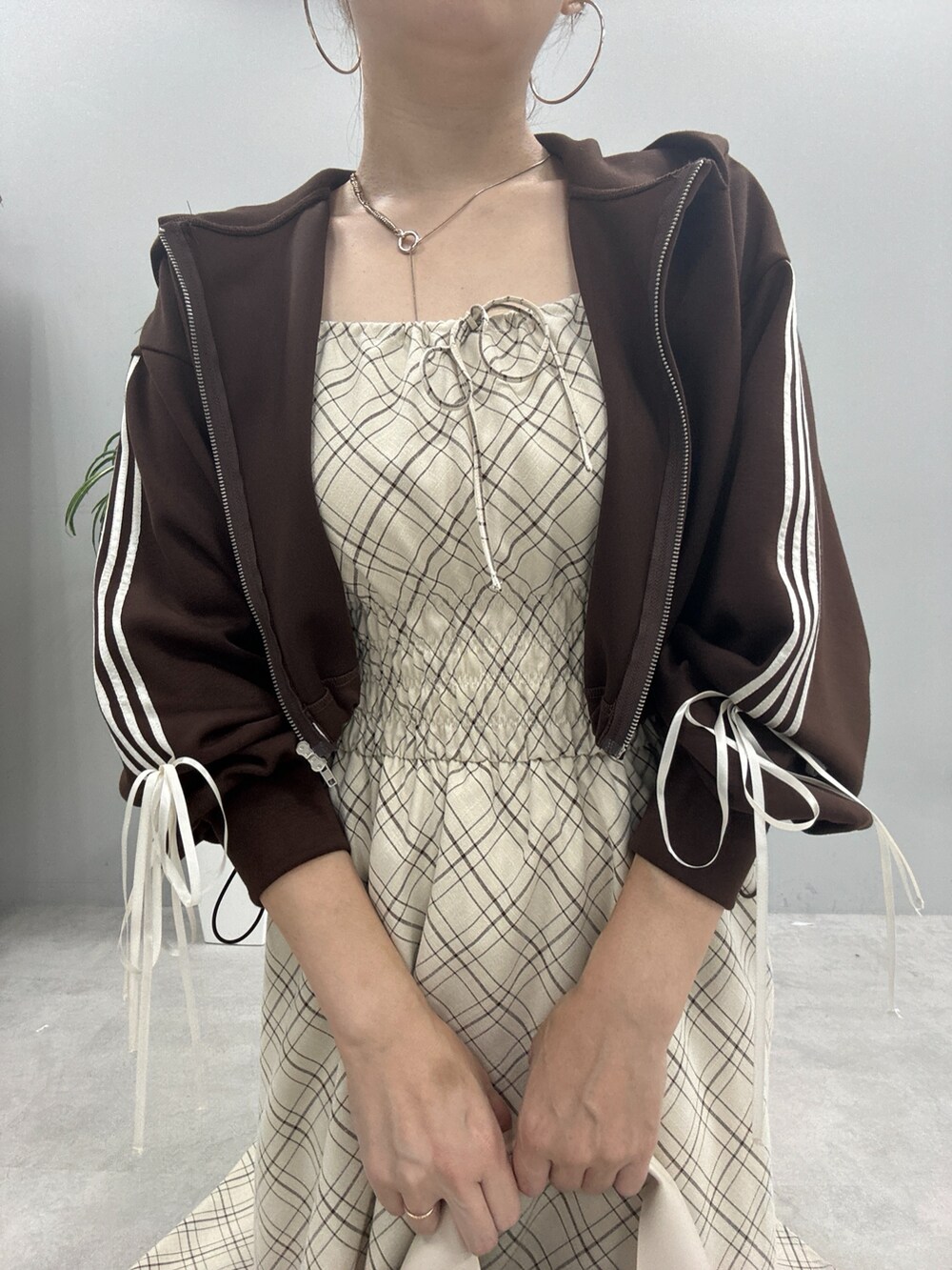 ブラウン系のパーカー、ブラック系のブーツ、ベージュ系のワンピースを着用したレディースの秋コーディネートの5枚目の写真