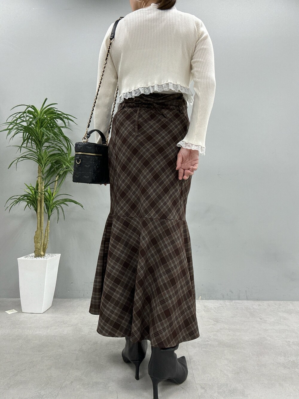 ブラウン系のスカート、ブラック系のショルダーバッグ、ホワイト系のカーディガン/ボレロを着用したレディースの秋コーディネートの3枚目の写真